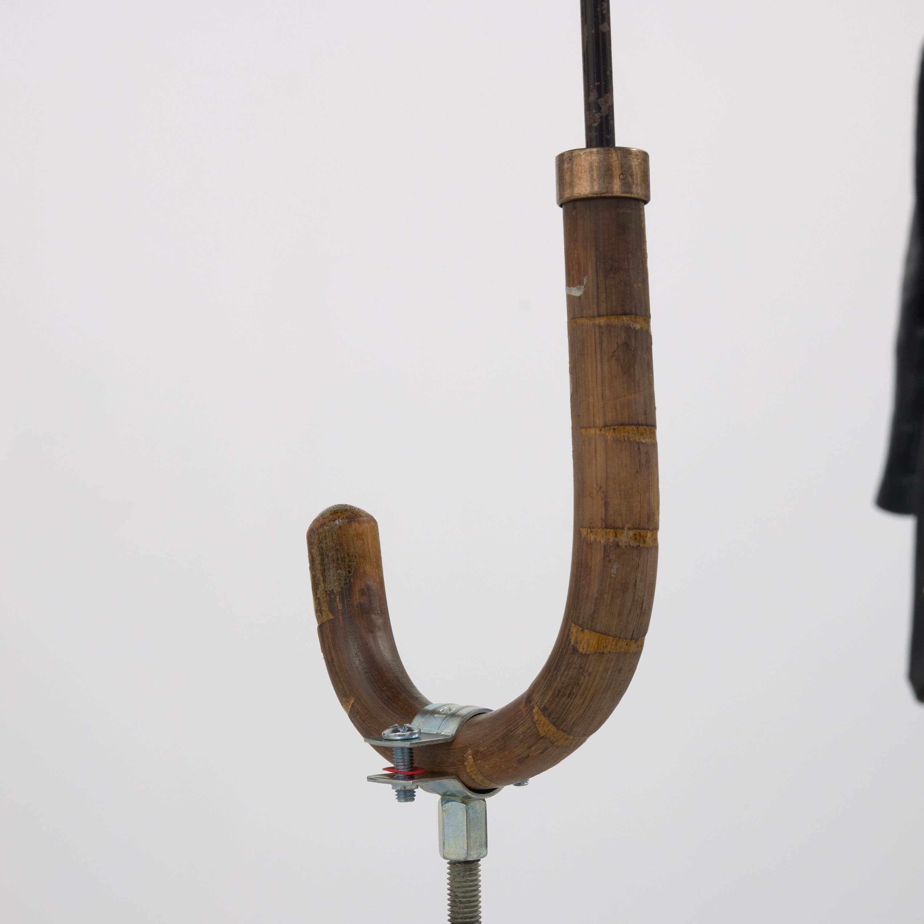 an image of Simeon Barclay's sculpture 'Warrior Falling on Their Feet', 2023 consiting of a Walking stick, umbrella, concrete, betting slip, foot fracture brace walker, bag for life