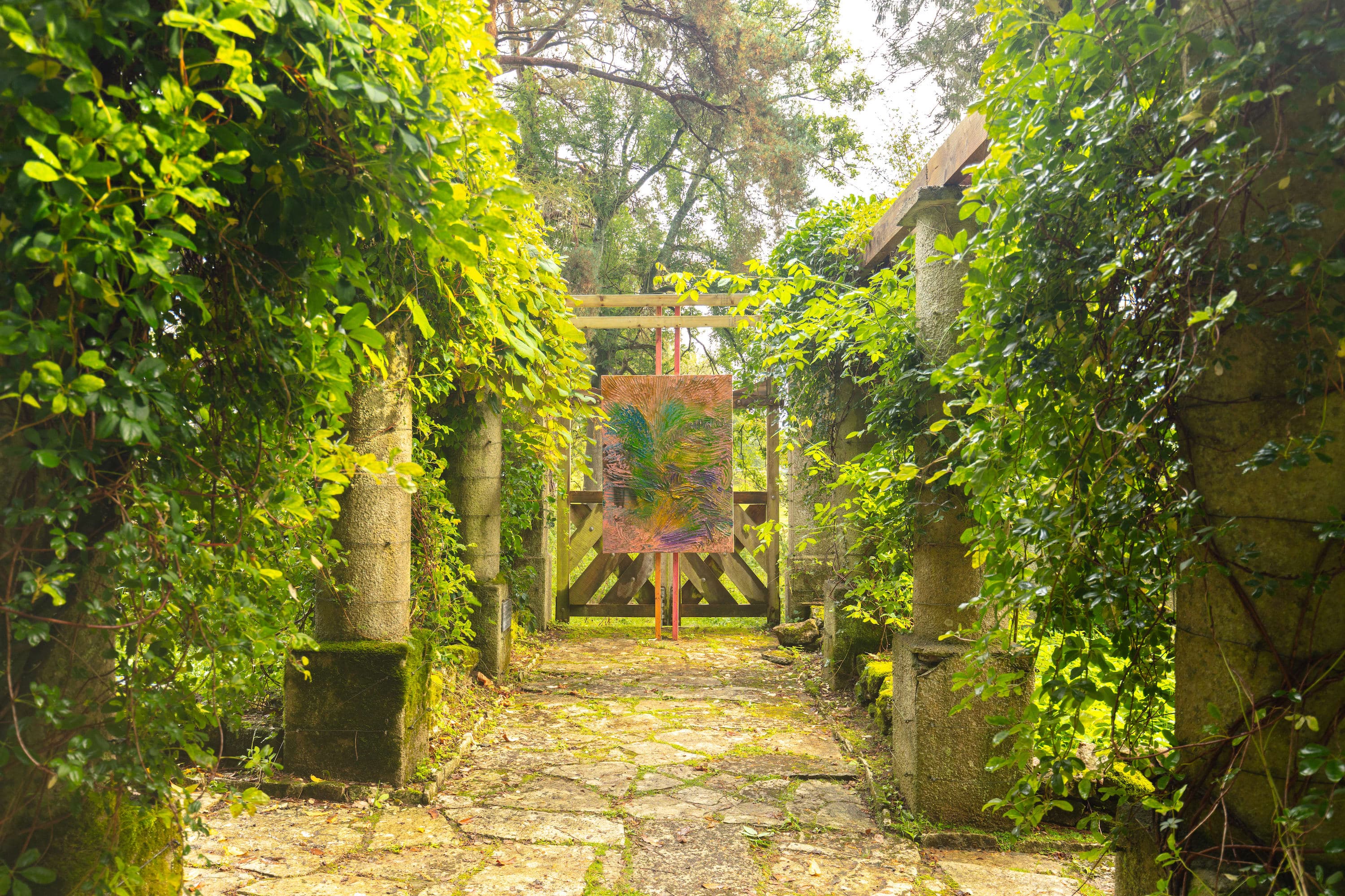 A painting by James Cabaniuk installed outside in a lush green garden