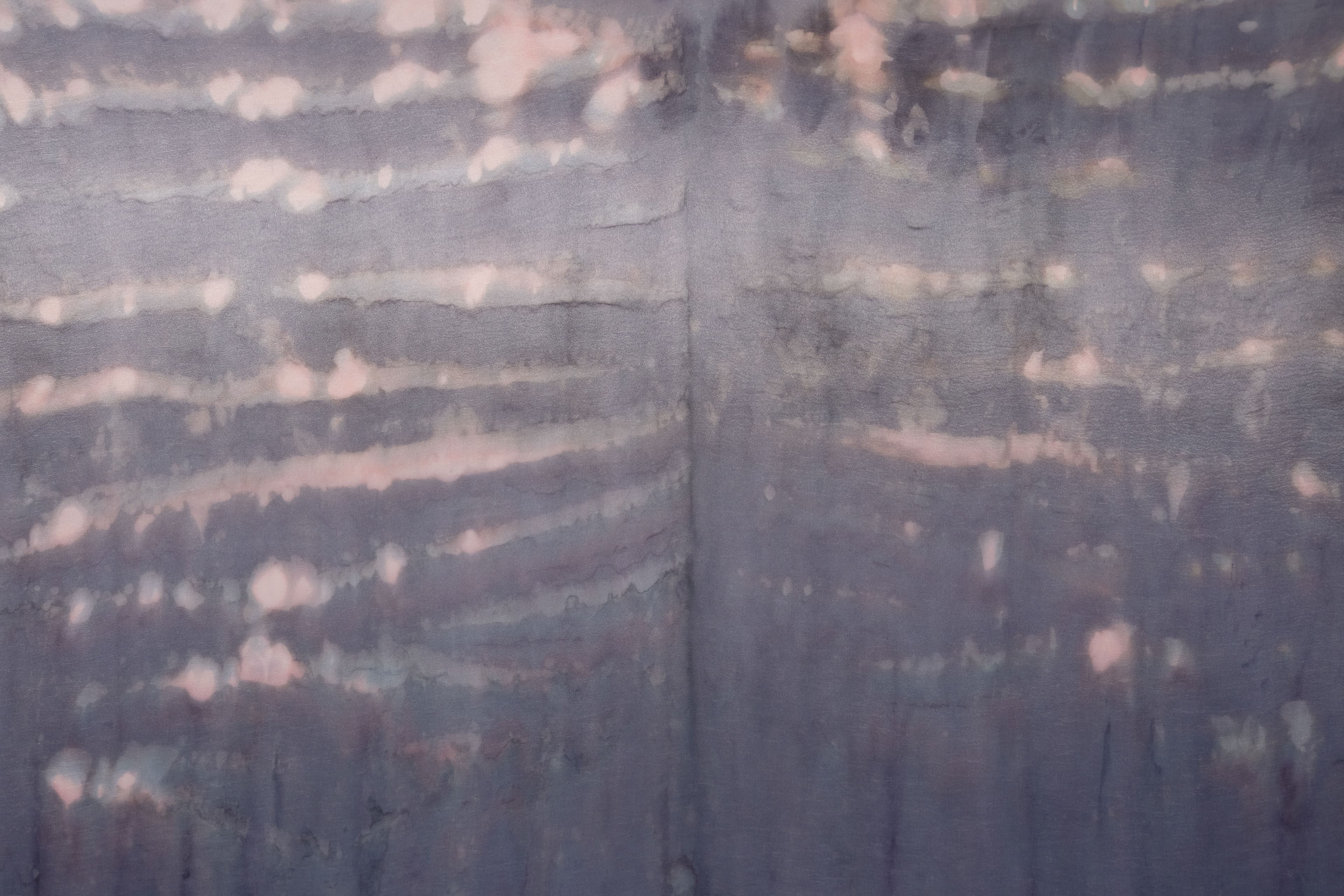 A large painting by Max Boyla. Dark purple background with a light bleached white and pink spot on the bottom of the canvas and lighter peach coloured markings on the top.