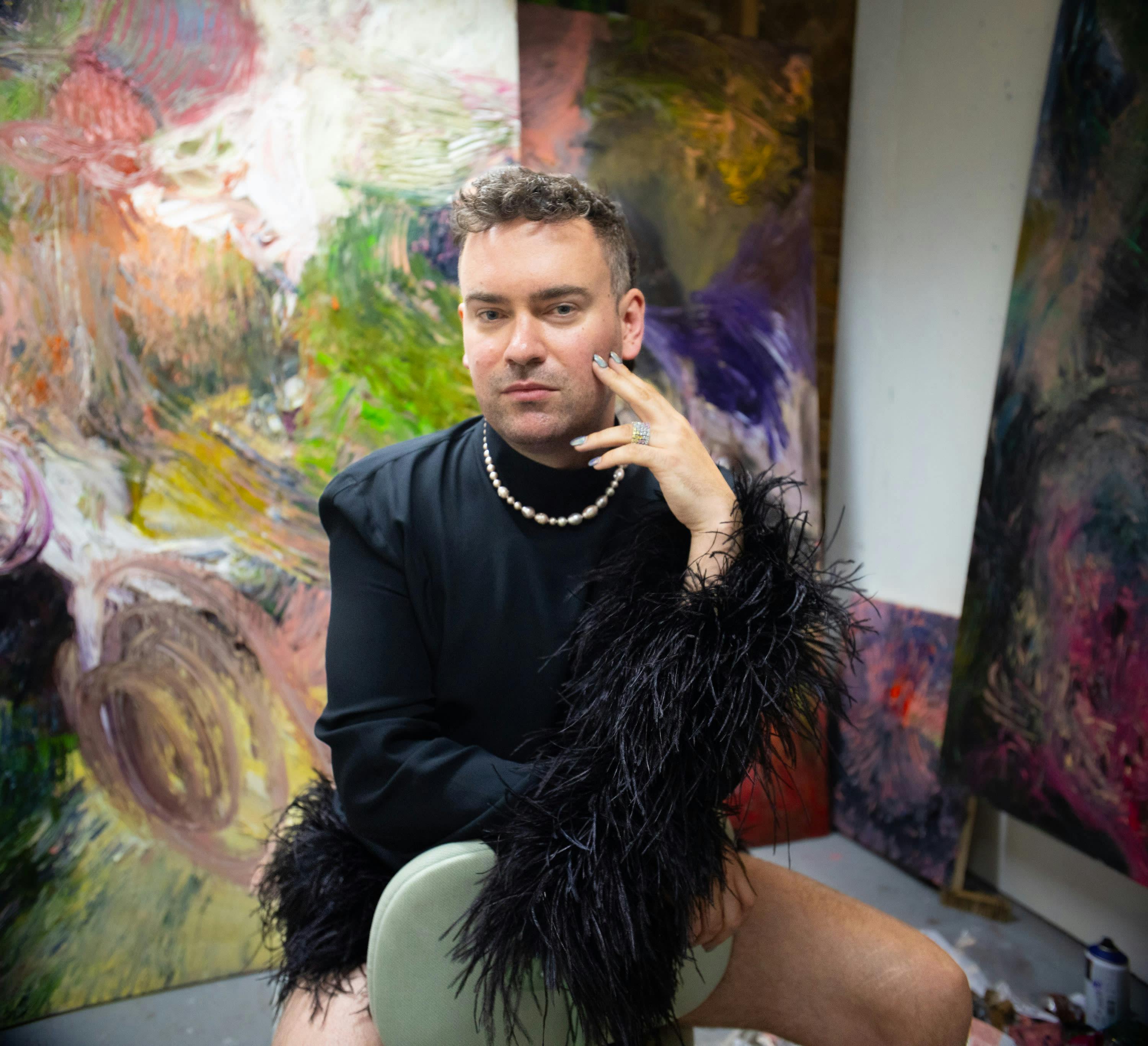 A portrait of James Cabaniuk with thick impasto abstract paintings behind them