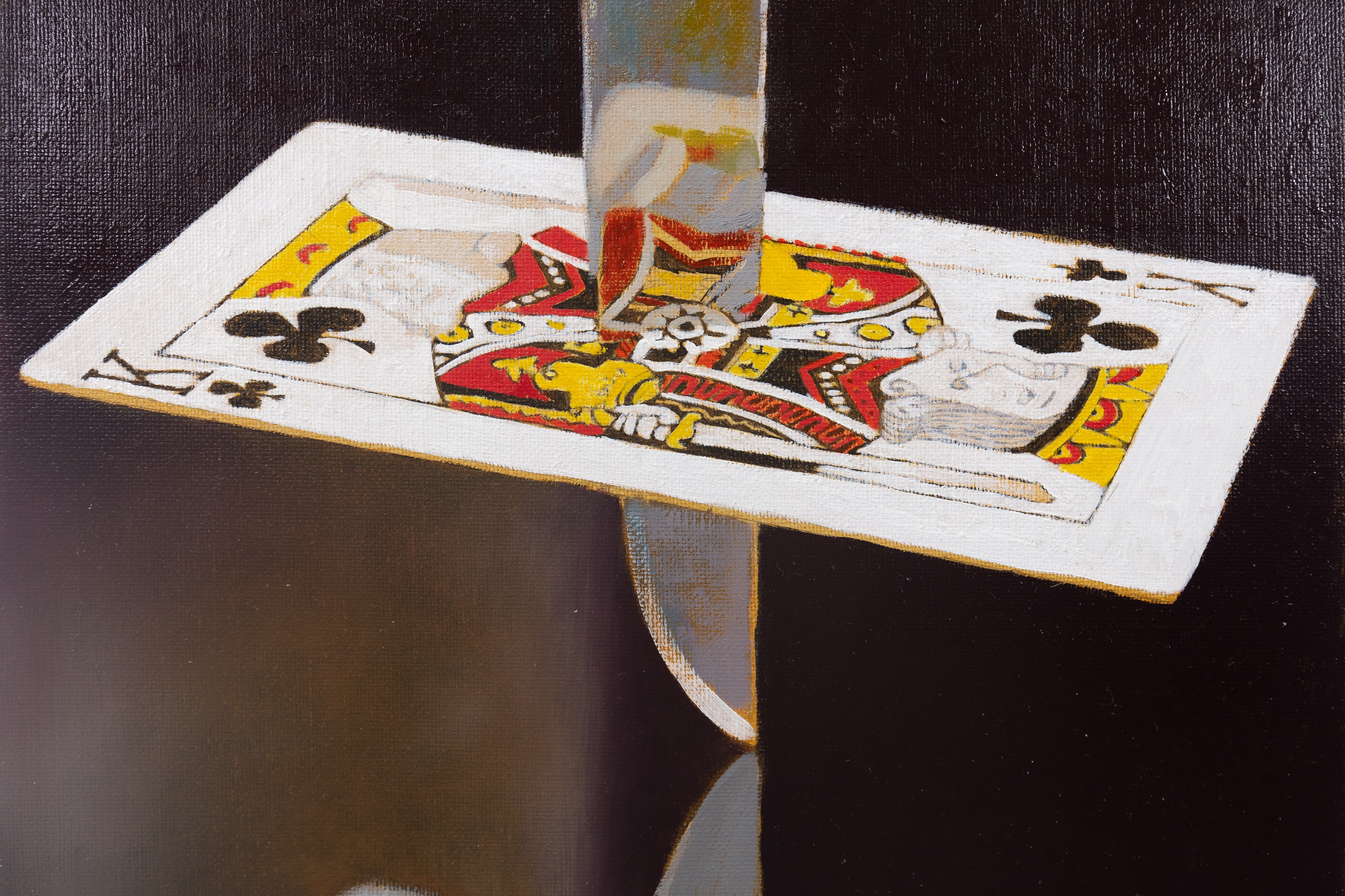 a dagger pierces a king of clubs card above a mirrored surface