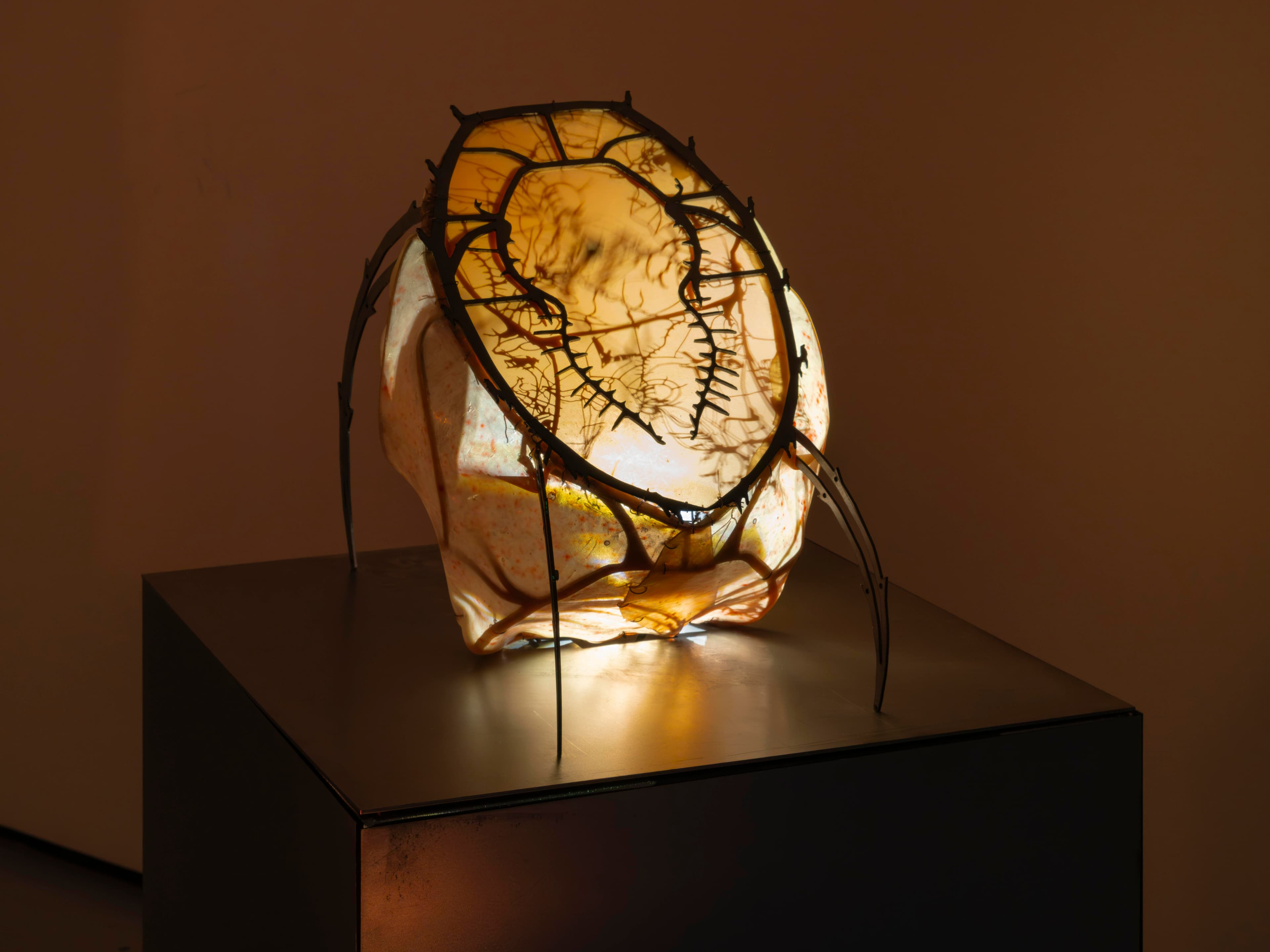 Medium sculpture displayed on metal plinth by Hazel Brill. Gem/crystal shape covered in latex skin with a alien microbe face and legs