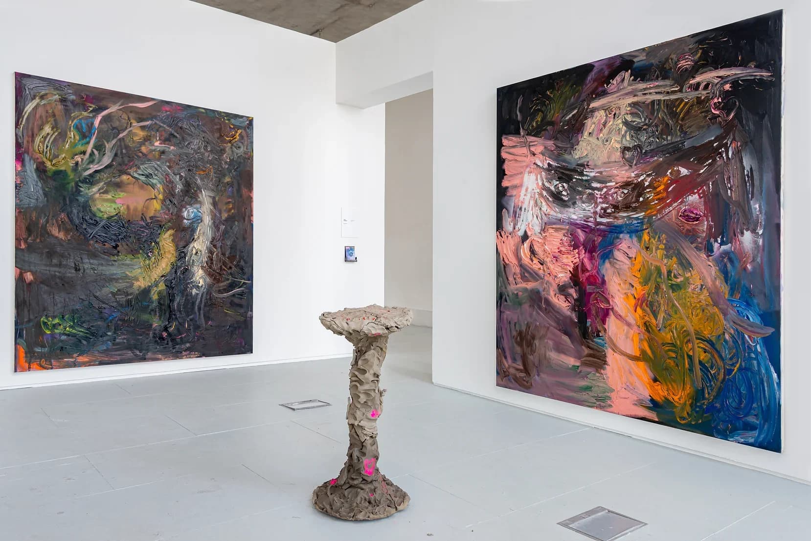 An installation by James Cabaniuk of 2 large abstract paintings and a clay sculpture on the floor