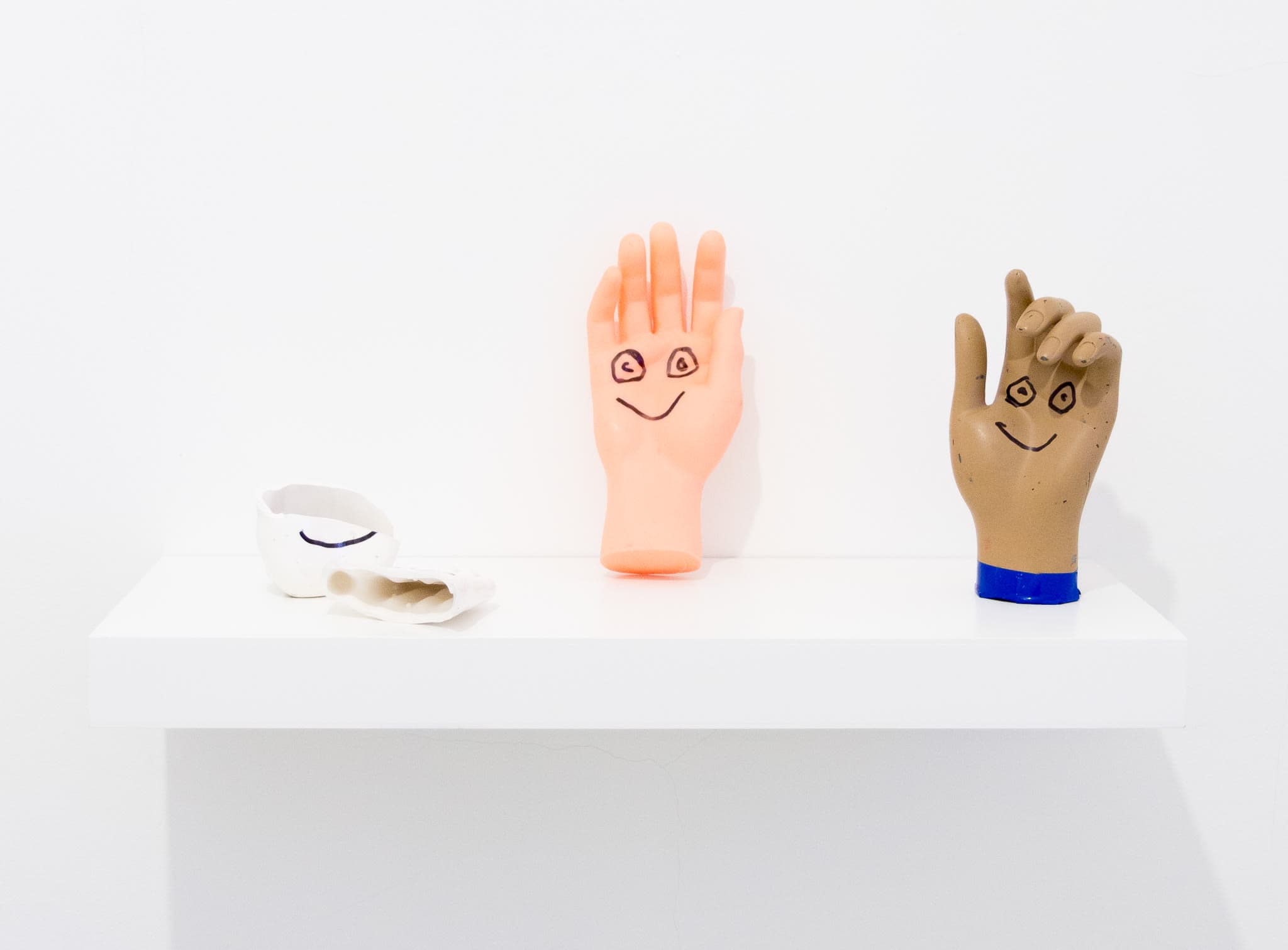 3 model hands which have smiley faces drawn on them by Joel Kyack as a remnant of a performance