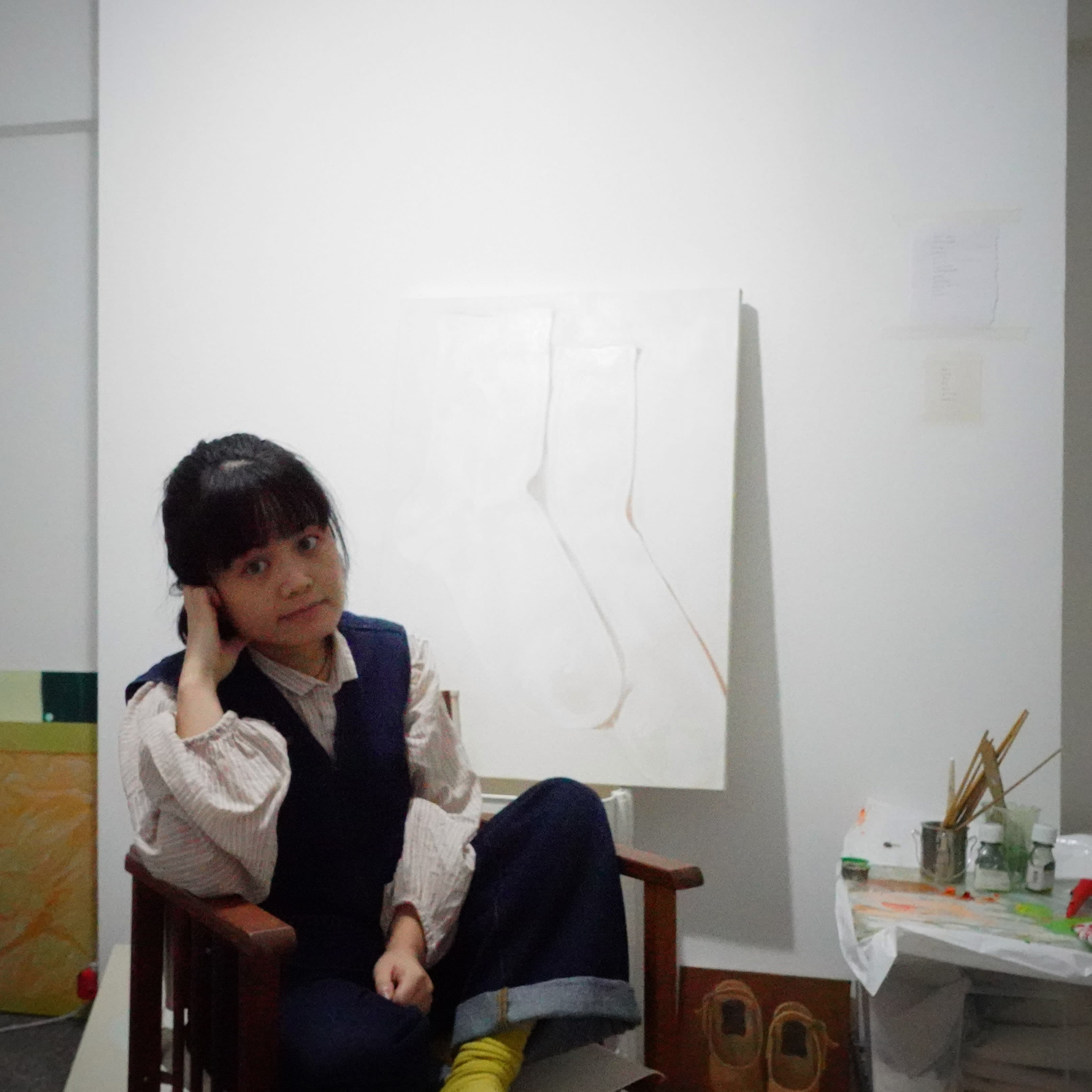 A portrait of Xingxin sat on a chair in her studio