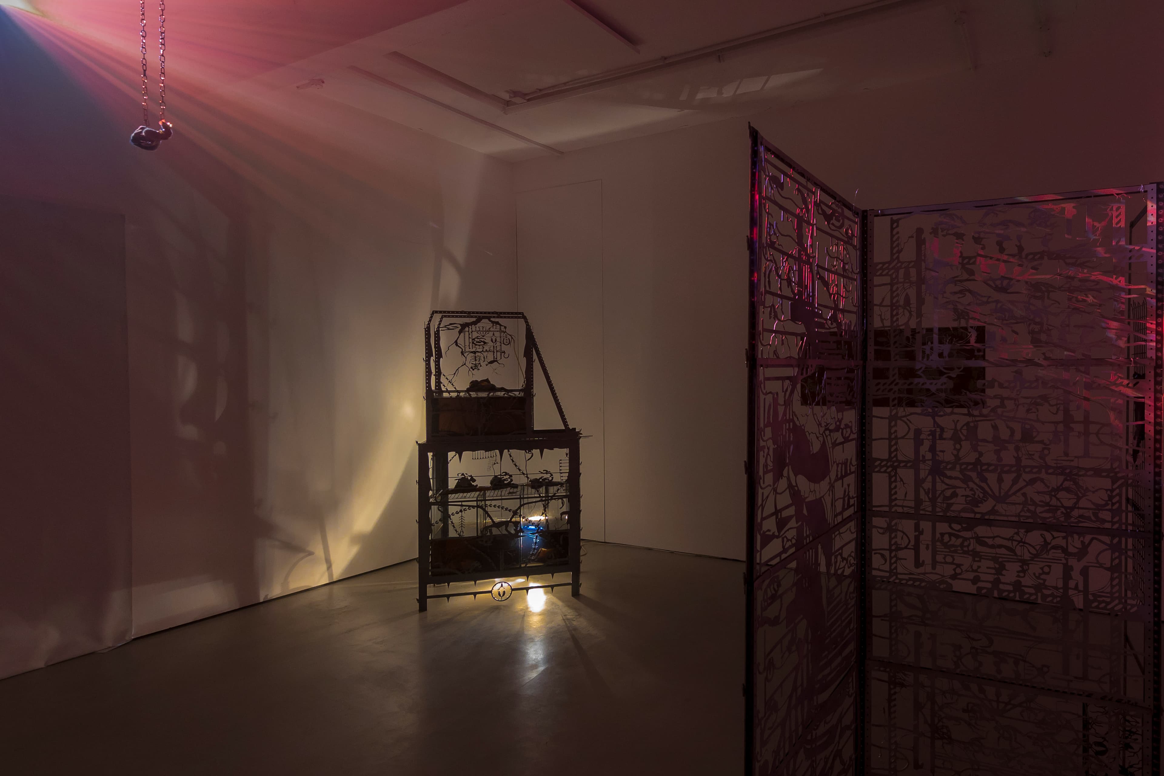 An installation by Hazel Brill including a water tanks filled with a dark liquid laser cut steel dividers, mouth-blown glass objects, projections and lights