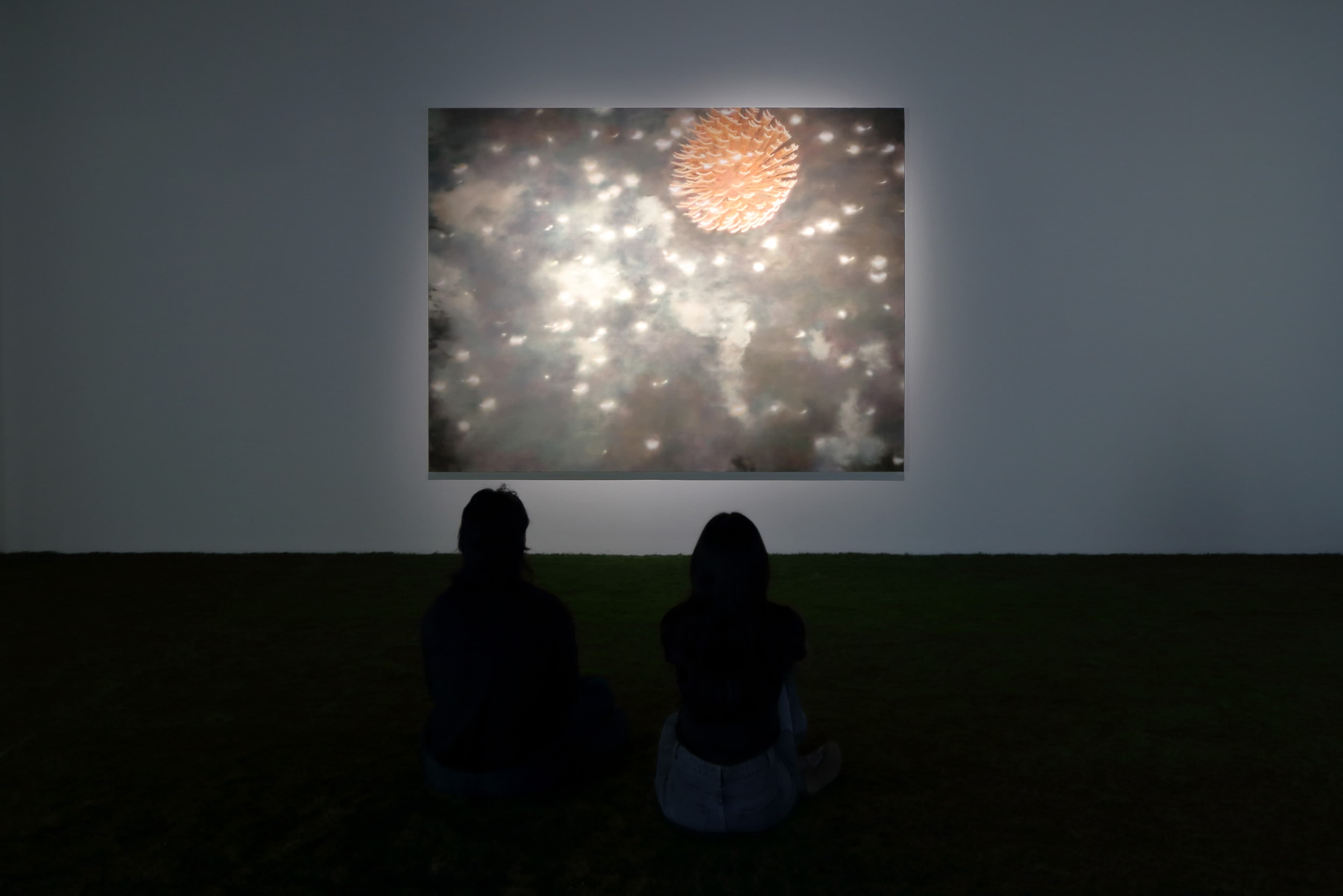 Installation view of a dark room with a painting by James Prapaithong softly spotlit