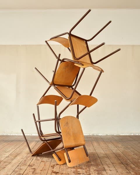 A sculpture by Jacob Dahlgren of a stack of wooden chairs