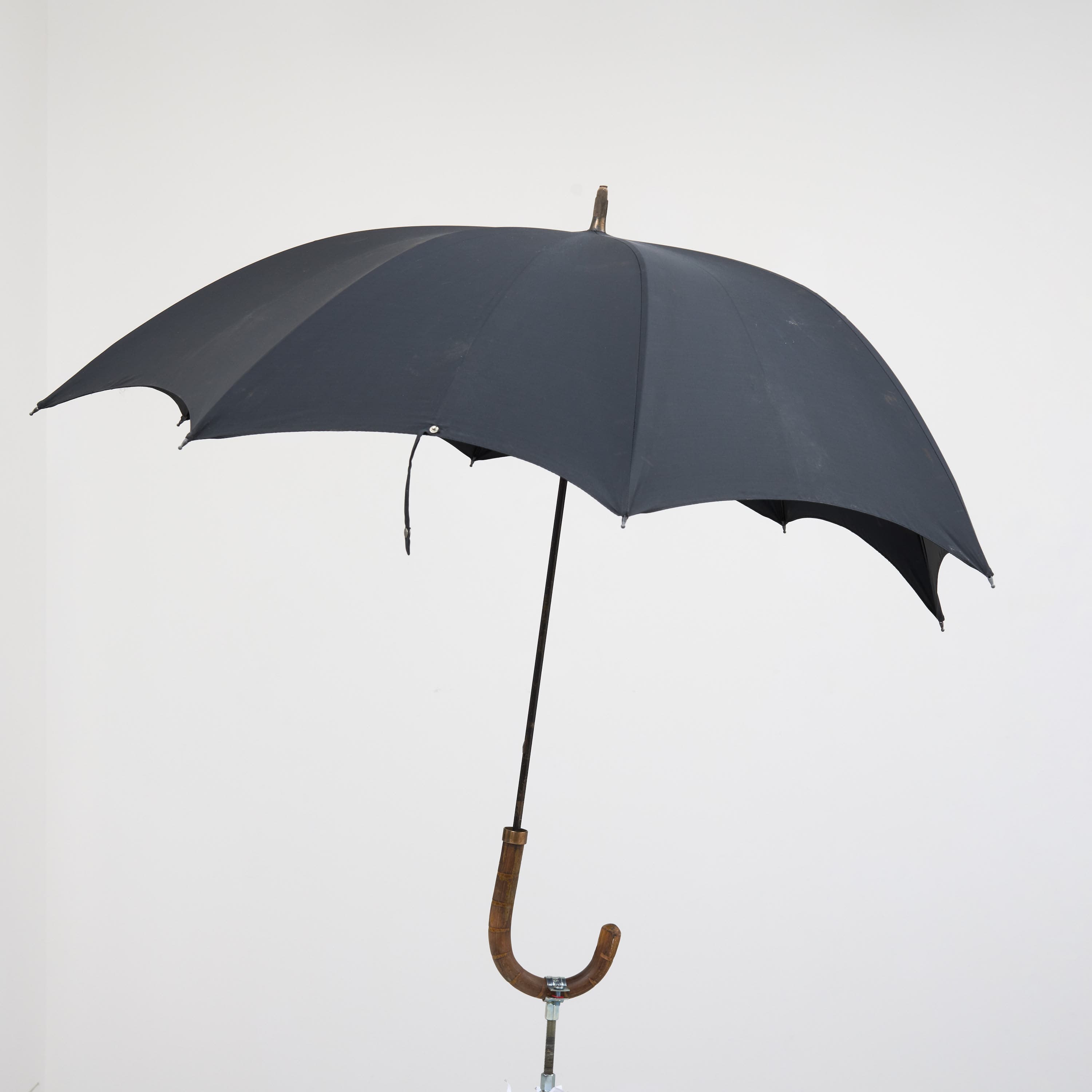 an image of Simeon Barclay's sculpture 'Warrior Falling on Their Feet', 2023 consiting of a Walking stick, umbrella, concrete, betting slip, foot fracture brace walker, bag for life