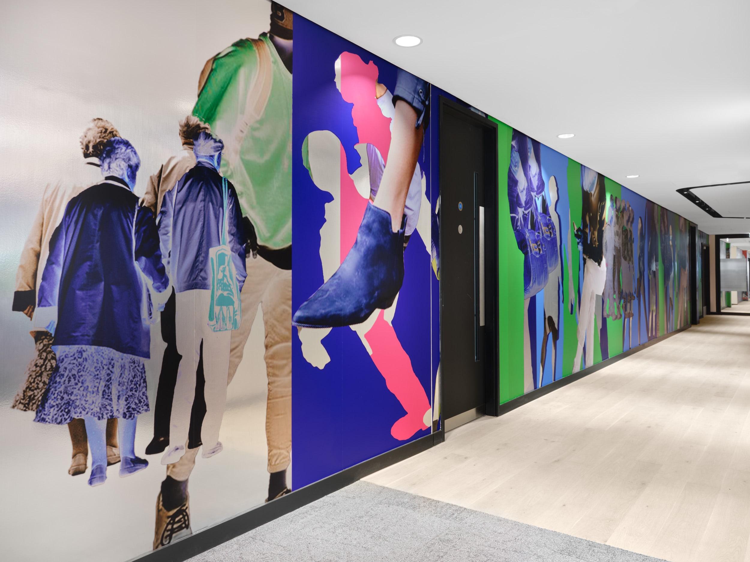 An installation by Simeon Barclay of bright collaged elements including people walking around an office space