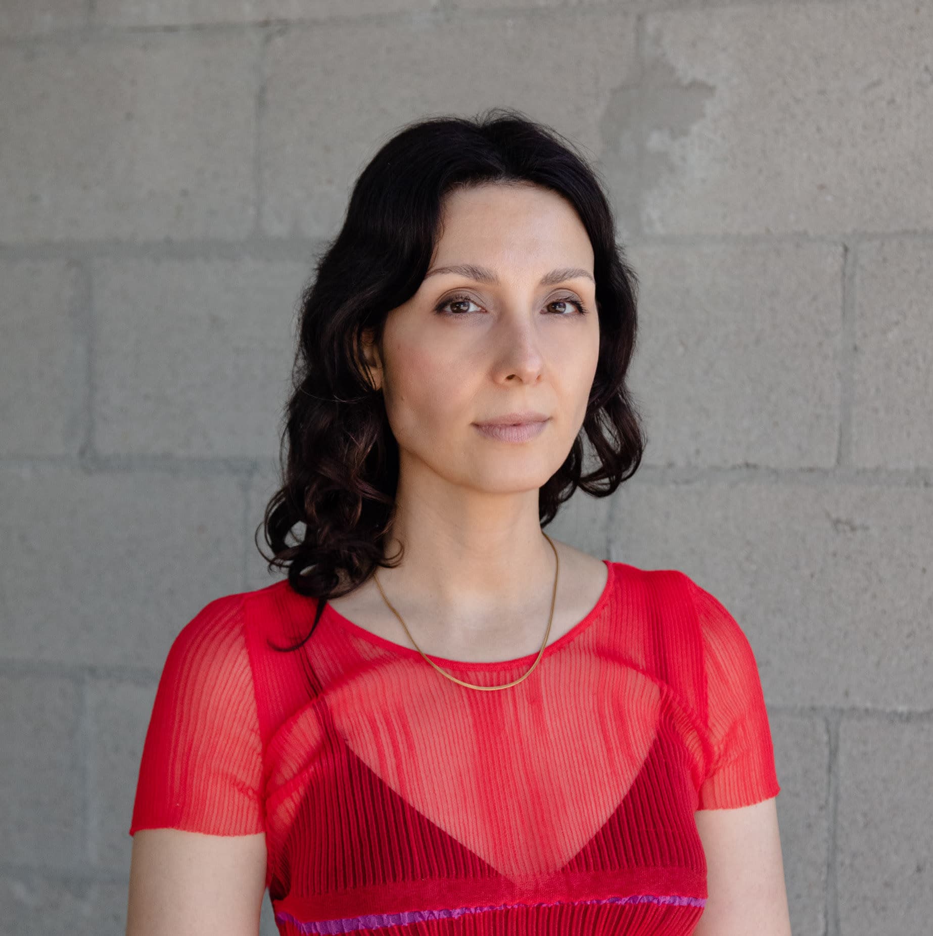 A portrait of Jennifer Carvalho stood against a grey brick wall