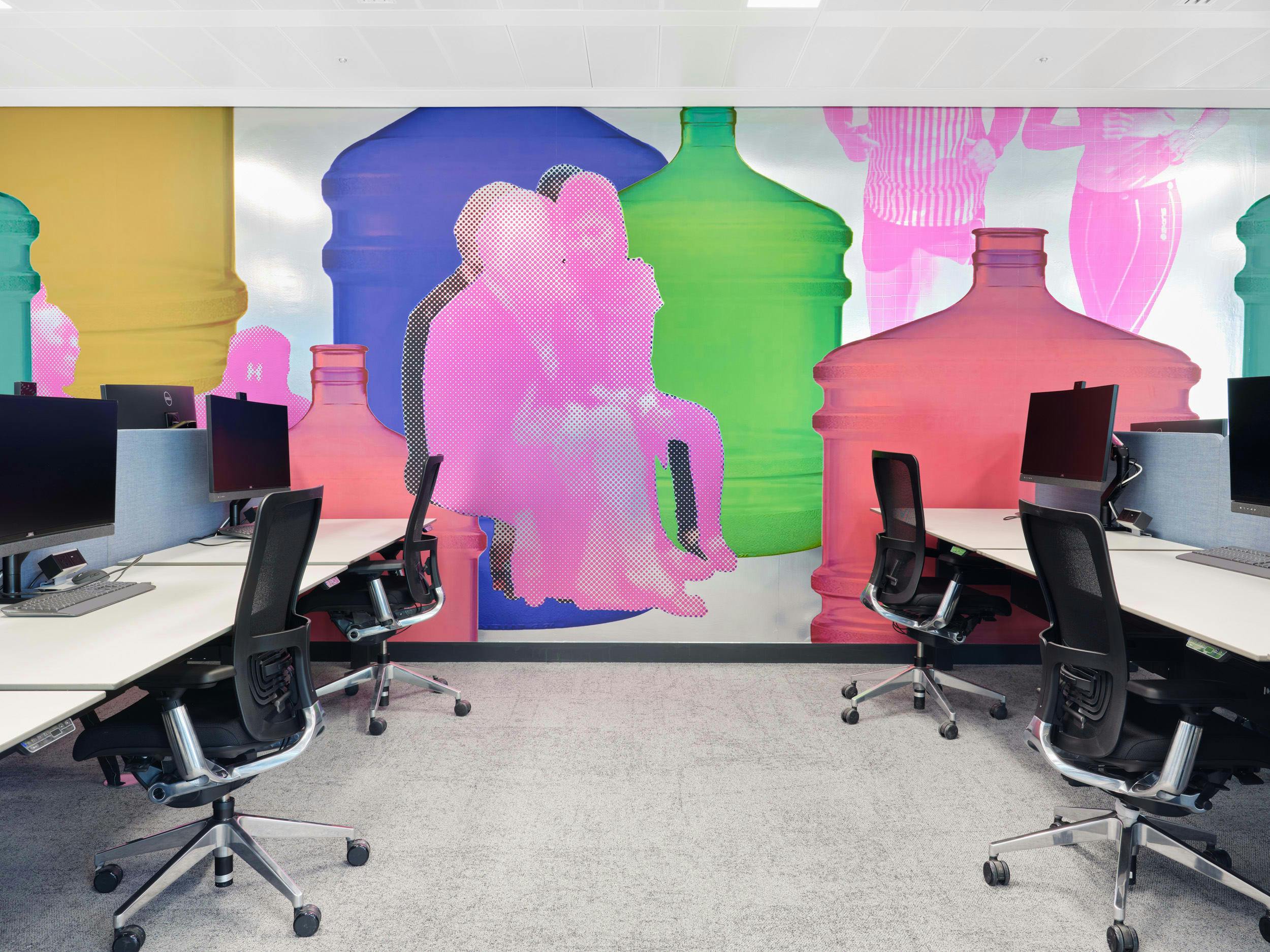 An installation by Simeon Barclay in an office composed of bright collaged people standing and walking