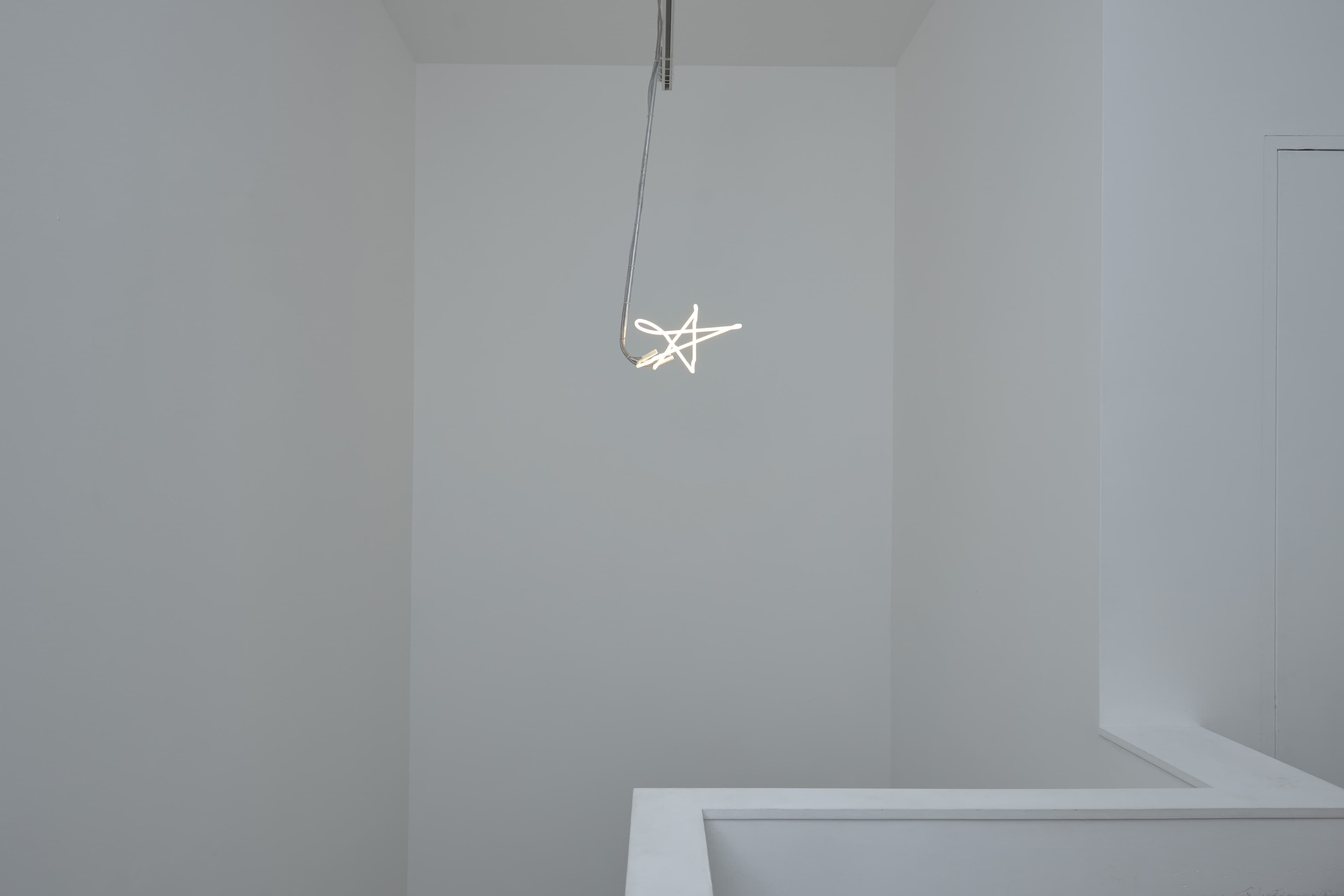 Neon light installation by Max Boyla. White, star shaped neon light suspended on a metal rod from the ceiling.