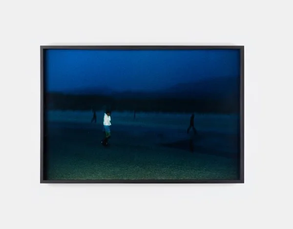 A photo by Nan Goldin of a figure standing on a dark beach