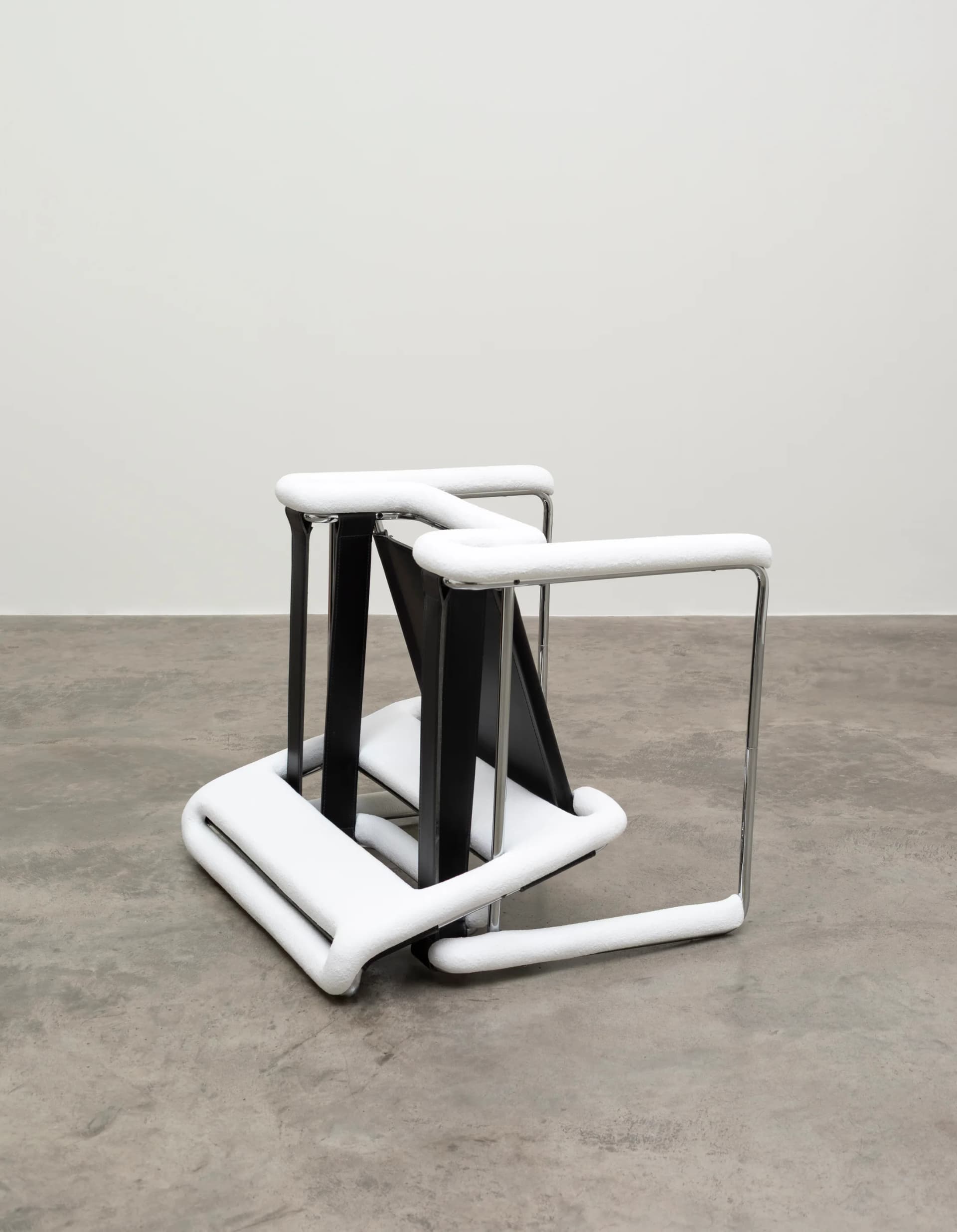 A sculpture by Ryan Gander with an upturned chair covered in snow